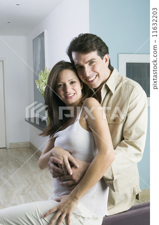 Hispanic couple hugging indoors 11632203