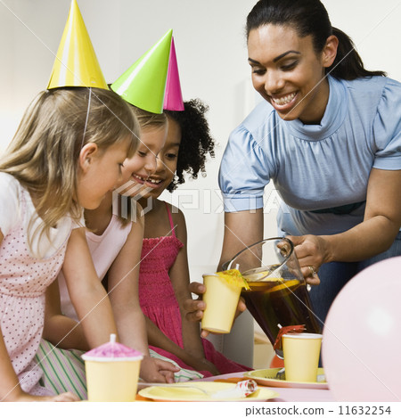Mixed Race woman pouring drink at daughter's party Mixed Race woman pouring drink at daughter's party 11632254