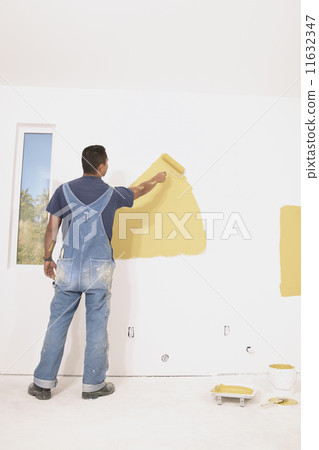 Rear view of man painting walls 11632347