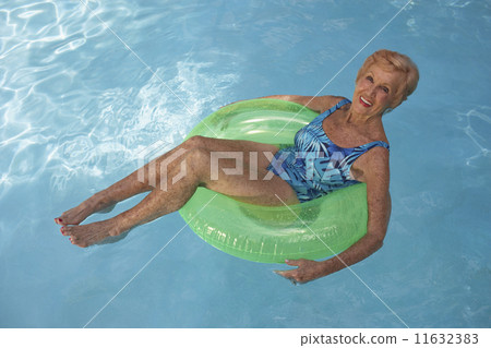 Senior woman floating in swimming pool 11632383