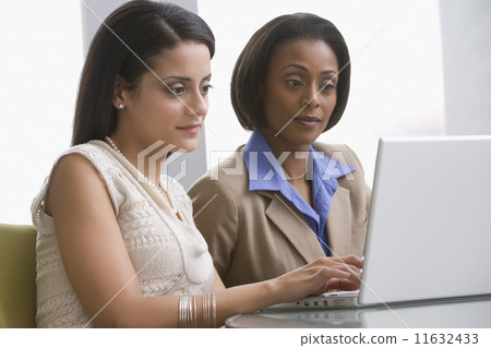 Multi-ethnic businesswomen looking at laptop Multi-ethnic businesswomen looking at laptop 11632433