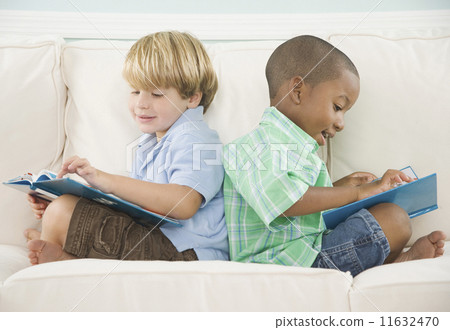 Two young boys reading on sofa 11632470