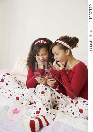 African twin sisters looking at cell phones 11632530