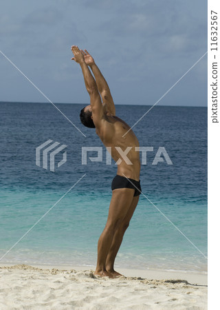 Hispanic man practicing yoga at beach 11632567