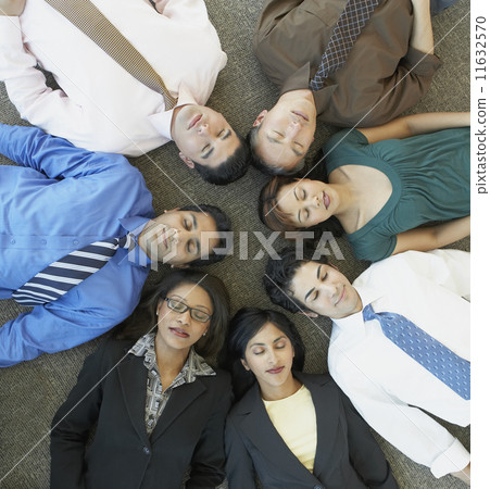 High angle view of businesspeople laying on floor with eyes closed 11632570