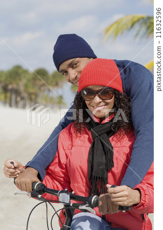 Multi-ethnic couple sitting on bicycle Multi-ethnic couple sitting on bicycle 11632596