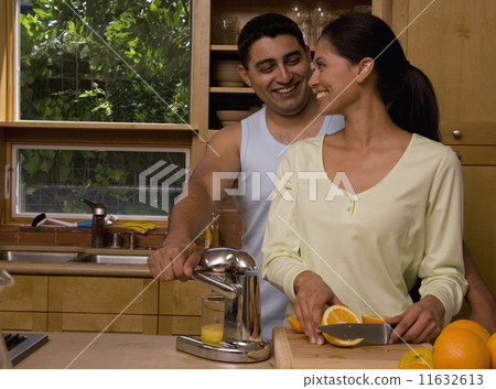 Multi-ethnic couple making orange juice Multi-ethnic couple making orange juice 11632613