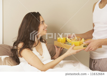 Hispanic woman receiving breakfast in bed  11632664