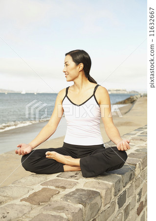 Asian woman meditating on wall Asian woman meditating on wall 11632667