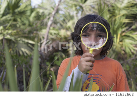 Hispanic boy looking through magnifying glass Hispanic boy looking through magnifying glass 11632668