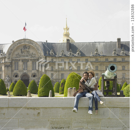 African couple hugging and sitting on stone wall next to cannon 11632886