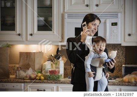 Hispanic mother on cell phone with baby in front pack 11632897