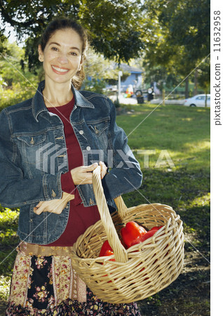 Middle Eastern woman carrying basket of organic produce Middle Eastern woman carrying basket of organic produce 11632958