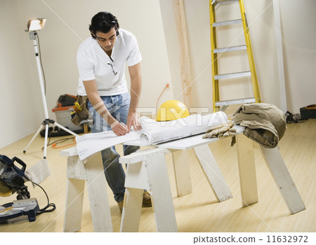 Mixed Race man writing on blueprints 11632972