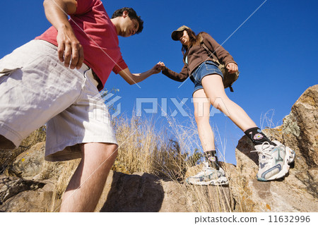 Hispanic man helping girlfriend on rocky hill Hispanic man helping girlfriend on rocky hill 11632996