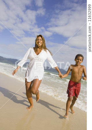Hispanic mother and son running in the surf 11632999