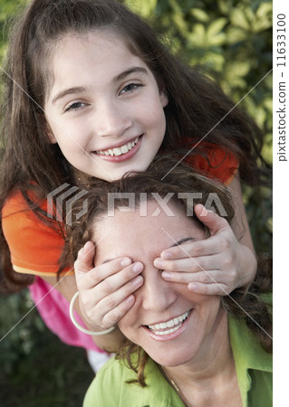 Hispanic girl covering mother's eyes 11633100