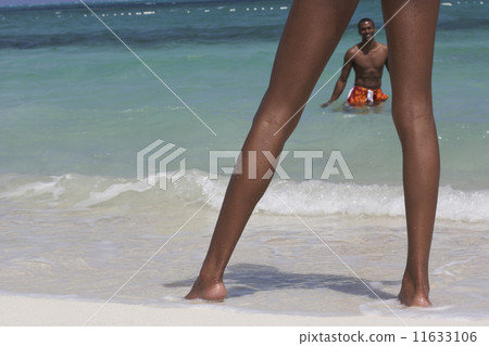 View through woman's legs to man in ocean View through woman's legs to man in ocean 11633106