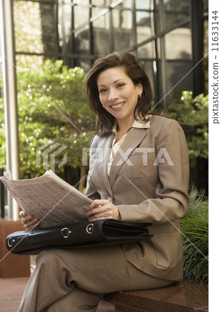 Hispanic businesswoman holding newspaper 11633144