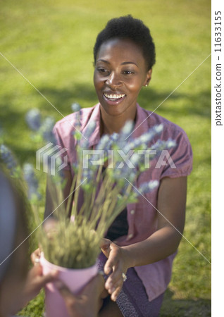 African woman reaching for potted plant 11633155