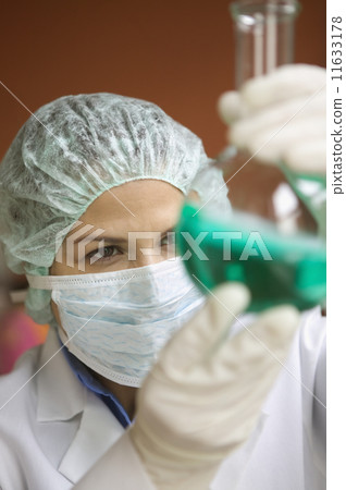 Woman in lab studying liquid in vial 11633178