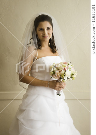 Hispanic bride holding bouquet 11633191