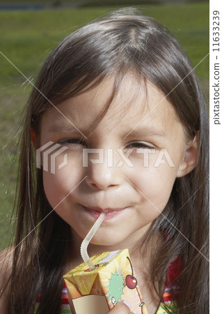 Young girl drinking out of a juice box 11633239