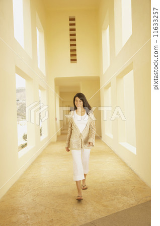Woman walking down sunlit hallway  11633257