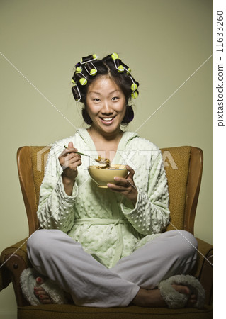 Asian woman in curlers eating cereal Asian woman in curlers eating cereal 11633260