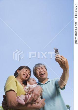 Asian grandparents holding baby grandchild and taking photograph Asian grandparents holding baby grandchild and taking photograph 11633276