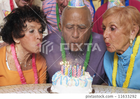 Senior Mixed Race man blowing out birthday candles 11633292
