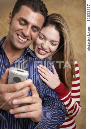 Hispanic couple looking at cell phone Hispanic couple looking at cell phone 11633317