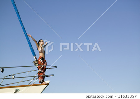 Asian woman on bow of sailboat with arms raised Asian woman on bow of sailboat with arms raised 11633357