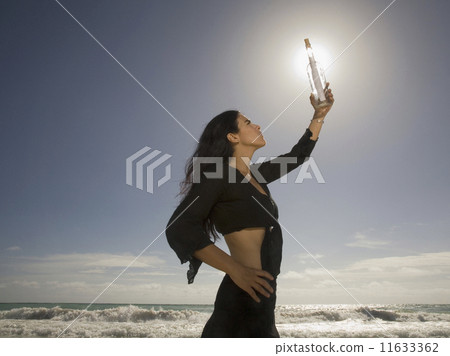 Hispanic woman holding message in bottle 11633362