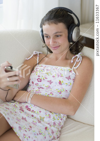 Girl listening to music on sofa Girl listening to music on sofa 11633367
