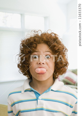 Mixed Race boy blowing bubble gum bubble 11633370