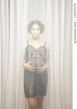 Pregnant Mixed Race woman standing behind curtains 11633479