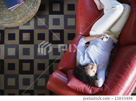 Woman on couch listening to music Woman on couch listening to music 11633494
