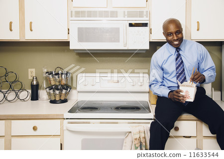 African man eating take out food in kitchen African man eating take out food in kitchen 11633544