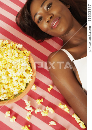 African woman laying next to popcorn bowl African woman laying next to popcorn bowl 11633557