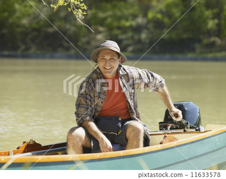 Hispanic man smiling in small boat Hispanic man smiling in small boat 11633578