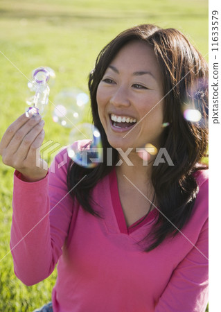 Asian woman blowing bubbles Asian woman blowing bubbles 11633579