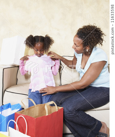 African mother showing young daughter new clothes African mother showing young daughter new clothes 11633598