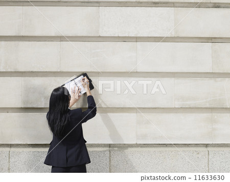 Hispanic businesswoman writing in planner 11633630