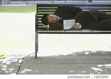 Asian businessman sleeping on park bench 11633665