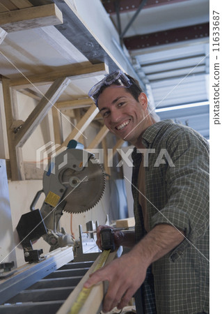 Hispanic man measuring piece of wood Hispanic man measuring piece of wood 11633687