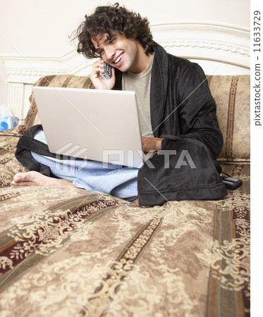 Hispanic man talking on telephone in bed 11633729