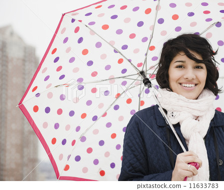 Hispanic woman walking in city with umbrella Hispanic woman walking in city with umbrella 11633783