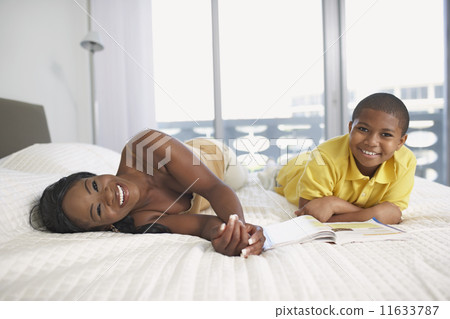 African American mother and son laying on bed 11633787