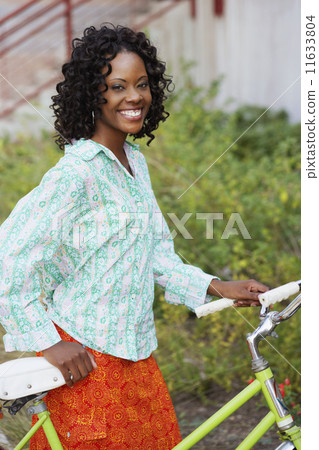 African woman walking bicycle outdoors African woman walking bicycle outdoors 11633804